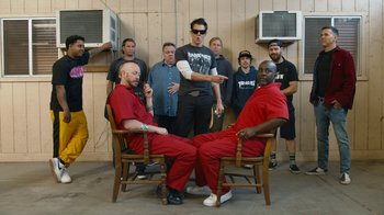 Movie still from “Jackass Forever” (2022), directed by Jeff Tremaine – A group of men sitting in chairs in a room; Medium shot, Low angle