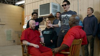 Movie still from “Jackass Forever” (2022), directed by Jeff Tremaine – A group of men sitting in a rocking chair; Medium shot, Over the shoulder angle