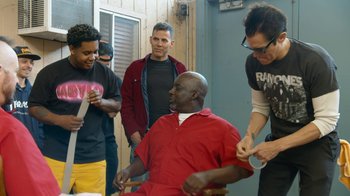 Movie still from “Jackass Forever” (2022), directed by Jeff Tremaine – A group of people standing around a man in a red shirt; Medium shot, Over the shoulder angle