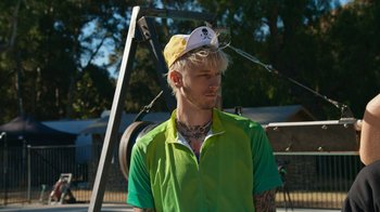 Movie still from “Jackass Forever” (2022), directed by Jeff Tremaine – A man in a green shirt wearing a white hat; Close Up shot, Over the shoulder angle
