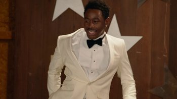 Movie still from “Jackass Forever” (2022), directed by Jeff Tremaine – A man in a white suit and black bow tie; Medium shot, Over the shoulder angle