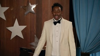 Movie still from “Jackass Forever” (2022), directed by Jeff Tremaine – A man in a white suit and a black bow tie; Medium shot, Over the shoulder angle