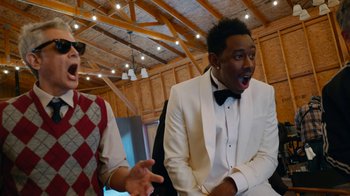 Movie still from “Jackass Forever” (2022), directed by Jeff Tremaine – A man in a white suit and a man in a black bow tie; Medium shot, Over the shoulder angle