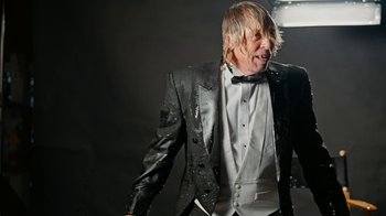 Movie still from “Jackass Forever” (2022), directed by Jeff Tremaine – A man in a suit and bow tie; Medium shot, Low angle