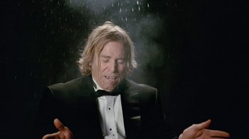 Movie still from “Jackass Forever” (2022), directed by Jeff Tremaine – A man in a tuxedo is standing in the rain; Close Up shot, Low angle