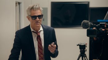 Movie still from “Jackass Forever” (2022), directed by Jeff Tremaine – A man in a suit and tie holding a cell phone; Medium shot, Low angle