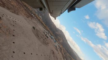 Movie still from “Jackass Forever” (2022), directed by Jeff Tremaine – An aerial view of vehicles parked on the side of a mountain; Extreme Wide shot, High angle