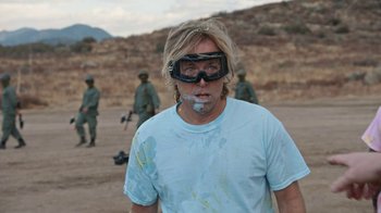 Movie still from “Jackass Forever” (2022), directed by Jeff Tremaine – A man with a gas mask on his face; Medium shot, Over the shoulder angle