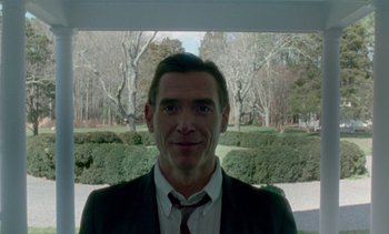 Movie still from “Jackie” (2016), directed by Pablo Larraín – A person wearing a suit and tie; Medium shot, Low angle