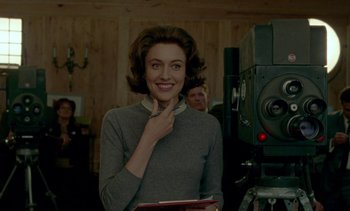 Movie still from “Jackie” (2016), directed by Pablo Larraín – A woman in a grey sweater is smiling for the camera; Medium shot, Over the shoulder angle