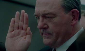 Movie still from “Jackie” (2016), directed by Pablo Larraín – A man in a suit and tie raising his hand; Close Up shot, Low angle