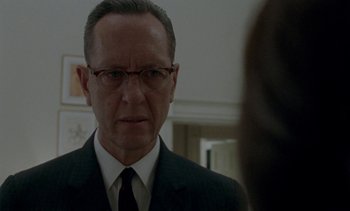 Movie still from “Jackie” (2016), directed by Pablo Larraín – A man in a suit and tie looking into the mirror; Close Up shot, Over the shoulder angle