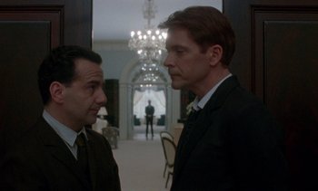 Movie still from “Jackie” (2016), directed by Pablo Larraín – Two men in suits standing next to each other in a room; Medium shot, Over the shoulder angle