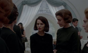 Movie still from “Jackie” (2016), directed by Pablo Larraín – Two women standing next to each other in front of a window; Medium shot, Low angle