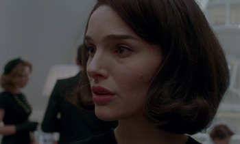 Movie still from “Jackie” (2016), directed by Pablo Larraín – A person with short brown hair; Close Up shot, Over the shoulder angle