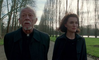 Movie still from “Jackie” (2016), directed by Pablo Larraín – A man and a woman walking down a road; Medium shot, Low angle