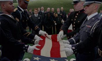 Movie still from “Jackie” (2016), directed by Pablo Larraín – A group of men in military uniforms holding an american flag; Wide shot, High angle