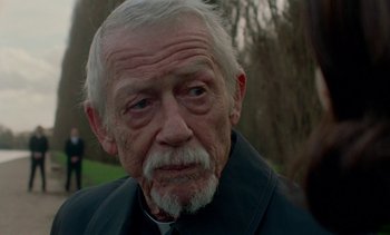 Movie still from “Jackie” (2016), directed by Pablo Larraín – An old man with a white beard looking at the camera; Close Up shot, Over the shoulder angle