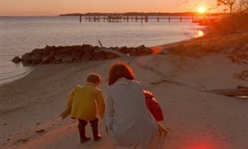 Movie still from “Jackie” (2016), directed by Pablo Larraín – A woman and a little girl walking on the beach at sunset; Wide shot, High angle