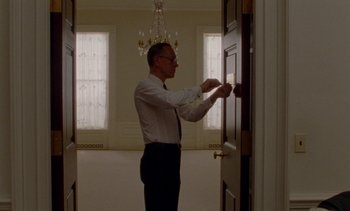 Movie still from “Jackie” (2016), directed by Pablo Larraín – A man in a suit and tie opening the door to a room; Medium shot, Low angle