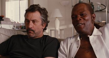 Movie still from “Jackie Brown” (1997), directed by Quentin Tarantino – Two men sitting next to each other in a living room; Close Up shot, Over the shoulder angle