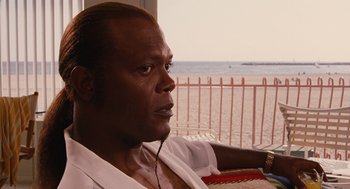 Movie still from “Jackie Brown” (1997), directed by Quentin Tarantino – A person wearing headphones near a body of water; Close Up shot, Over the shoulder angle