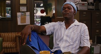 Movie still from “Jackie Brown” (1997), directed by Quentin Tarantino – A man sitting at a table with a cup of coffee; Medium shot, Low angle