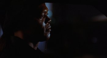 Movie still from “Jackie Brown” (1997), directed by Quentin Tarantino – A person wearing headphones looking up; Close Up shot, Over the shoulder angle