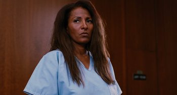Movie still from “Jackie Brown” (1997), directed by Quentin Tarantino – A woman with long hair is standing in front of a wall; Close Up shot, Low angle