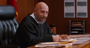 Movie still from “Jackie Brown” (1997), directed by Quentin Tarantino – A man sitting at a table in a court room; Medium shot, Low angle
