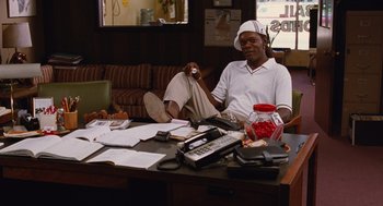 Movie still from “Jackie Brown” (1997), directed by Quentin Tarantino – A man sitting at a table in a room; Medium shot, Low angle