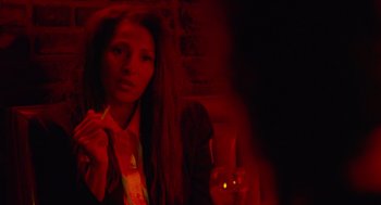 Movie still from “Jackie Brown” (1997), directed by Quentin Tarantino – A woman is smoking a cigarette in a dark room; Close Up shot, Over the shoulder angle