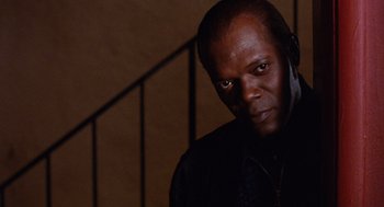 Movie still from “Jackie Brown” (1997), directed by Quentin Tarantino – A man in a black shirt is looking at the camera; Close Up shot, Low angle