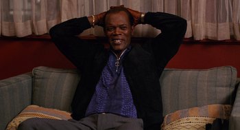 Movie still from “Jackie Brown” (1997), directed by Quentin Tarantino – A man sitting on a couch with his hands behind his head; Medium shot, High angle