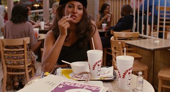 Movie still from “Jackie Brown” (1997), directed by Quentin Tarantino – A woman sitting at a table eating a donut; Medium shot, High angle