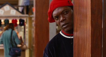 Movie still from “Jackie Brown” (1997), directed by Quentin Tarantino – A man in a red hat is leaning against a wall; Close Up shot, Over the shoulder angle