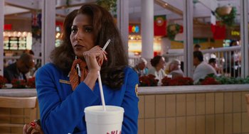 Movie still from “Jackie Brown” (1997), directed by Quentin Tarantino – A woman sitting at a table with a cup of coffee; Medium shot, Over the shoulder angle