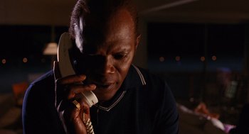 Movie still from “Jackie Brown” (1997), directed by Quentin Tarantino – A man is talking on a phone while sitting at a table; Close Up shot, High angle