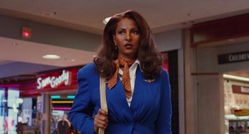 Movie still from “Jackie Brown” (1997), directed by Quentin Tarantino – A woman in a blue suit and orange neck tie; Medium shot, Low angle