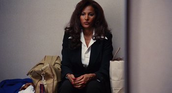 Movie still from “Jackie Brown” (1997), directed by Quentin Tarantino – A woman sitting on the ground with her hands crossed; Medium shot, Over the shoulder angle