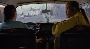 Movie still from “Jackie Brown” (1997), directed by Quentin Tarantino – A man driving a car in a city street; Medium shot, Over the shoulder angle