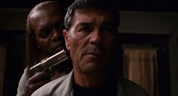 Movie still from “Jackie Brown” (1997), directed by Quentin Tarantino – A man with a gun in his hand and another man with a gun in his other hand; Close Up shot, Over the shoulder angle