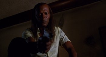 Movie still from “Jackie Brown” (1997), directed by Quentin Tarantino – A man holding a gun in a room; Close Up shot, Low angle