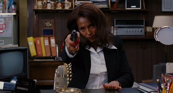 Movie still from “Jackie Brown” (1997), directed by Quentin Tarantino – A woman holding a gun pointed at the camera; Medium shot, Low angle