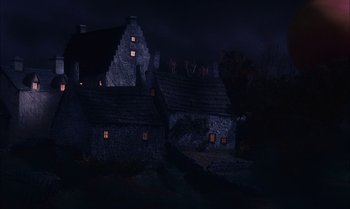 Movie still from “James and the Giant Peach” (1996), directed by Henry Selick – A dark night with some lights on the windows of a house; Extreme Wide shot, Low angle