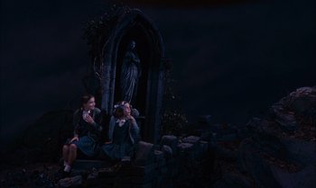 Movie still from “James and the Giant Peach” (1996), directed by Henry Selick – Two young girls sitting in front of a statue of a virgin mary; Wide shot, High angle