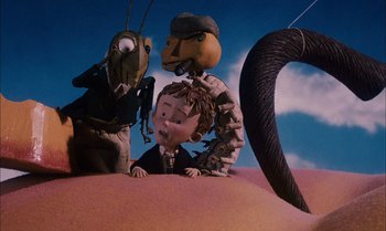Movie still from “James and the Giant Peach” (1996), directed by Henry Selick – A group of puppets that are sitting in the sand; Medium shot, High angle