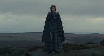 Movie still from “Jane Eyre” (2011), directed by Cary Joji Fukunaga – A woman standing on top of a hill wearing a cape; Wide shot, High angle