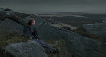 Movie still from “Jane Eyre” (2011), directed by Cary Joji Fukunaga – A woman sitting on top of a rock on top of a hill; Wide shot, High angle