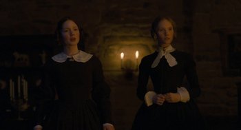 Movie still from “Jane Eyre” (2011), directed by Cary Joji Fukunaga – Two women in black dresses standing in front of candles; Medium shot, Low angle